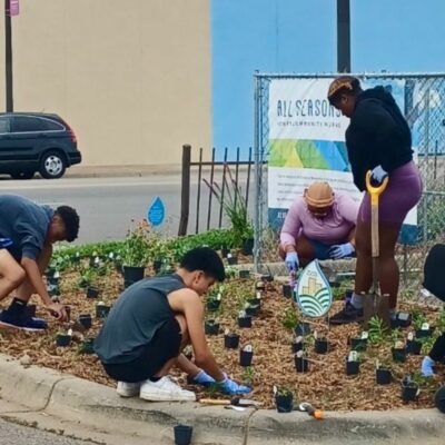 Group of people planting a corner garden in parking lot