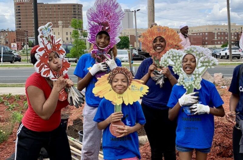 group of young people looking through flowers masks on sticks 