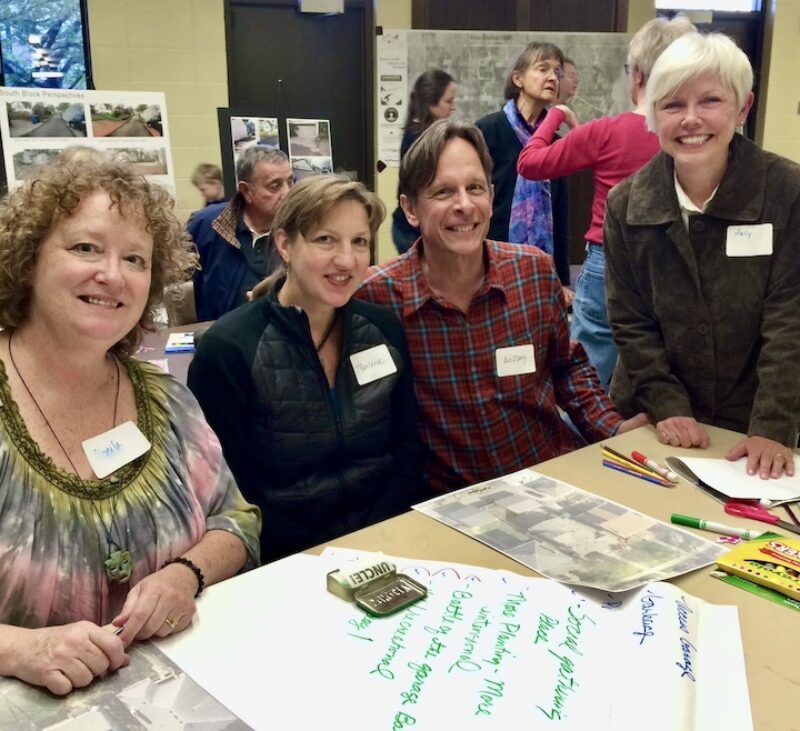 Four people with name tags at table looking at landscape design materials together