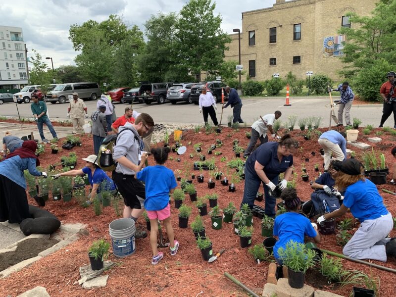 Youths, adults, elders planting a large community garden together