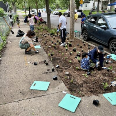 Mats for kneeling on sidewalks with people planting plants in a boulevard