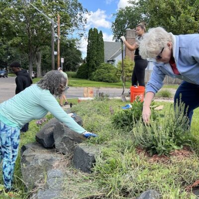 Two people pulling weeds in a yard as part of a yard maintenance workshops with Metro Blooms