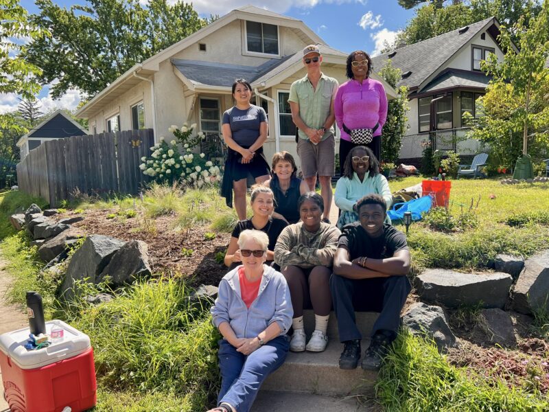community relations team and community members posing in front of a community planting project